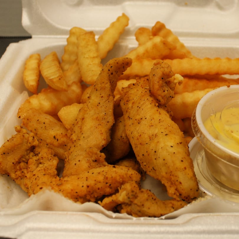 Joe's To Go Drive Thru chicken tenders and crinkle-cut fries with dipping sauce in a takeout container.