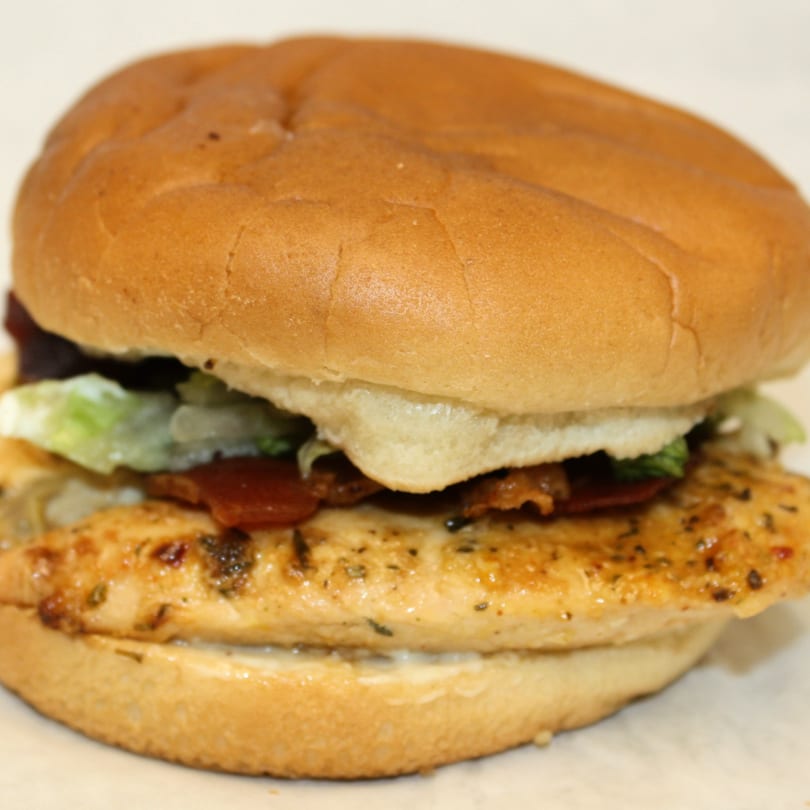Joe's To Go grilled chicken sandwich with bacon, lettuce, and mayonnaise on a bun.