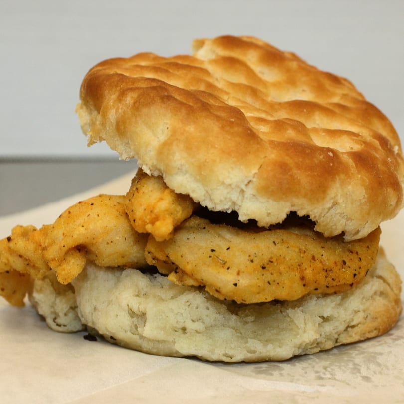Close-up of a golden-brown fried chicken patty on a fluffy biscuit from Joe's To Go.